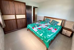 a bedroom with a bed with a green and white comforter at Taina - Terrasse - Bord de mer - in Opoa