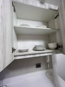 a kitchen with white plates and bowls on a shelf at Departamento frente al mar YMAS in La Serena