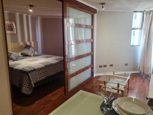 1 dormitorio con cama, mesa y espejo en San Ignacio Suite Apartments, en Santiago
