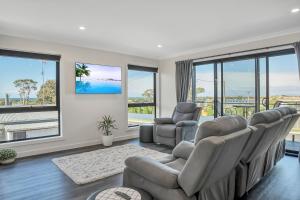 a living room with a couch and chairs and windows at Bridport by the Sea in Bridport