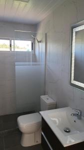 a white bathroom with a toilet and a sink at Complejo de casas en Pueblo Centenario in Paso de los Toros