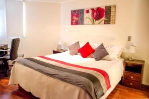 1 dormitorio con 1 cama grande con almohadas rojas en San Ignacio Suite Apartments, en Santiago