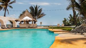 a swimming pool with a gazebo and palm trees at Villa Polinesia Chamela in Pérula