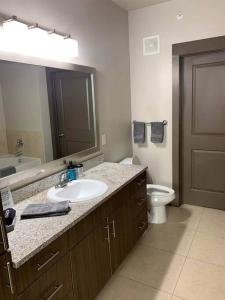 La salle de bains est pourvue d'un lavabo, de toilettes et d'un miroir. dans l'établissement Business District Double Master w/ Pool!, à Houston
