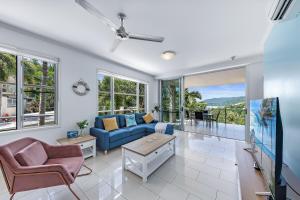 sala de estar con sofá azul y sillas en Airlie Summit Apartments, en Airlie Beach