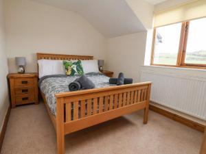 a bedroom with a wooden bed and a window at Maes Yr Haf in Rhyl