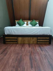 a bed with a wooden headboard and green pillows at Misty Ghats Resort in Wayanad