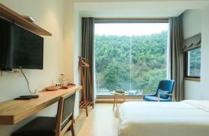 a hotel room with a desk and a large window at Villa EN Emerald Valley, Huangshan in Huangshan Scenic Area