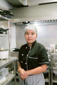 a woman standing in a kitchen with her arms crossed at LM Hoteles in Piura