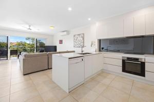 a kitchen with white cabinets and a couch at Unit 6 Taralla 16 18 Edgar Bennett Avenue Noosa Heads in Noosa Heads