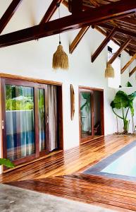 salon z drewnianymi podłogami i oknami w obiekcie Yumi Villas w mieście San Vicente
