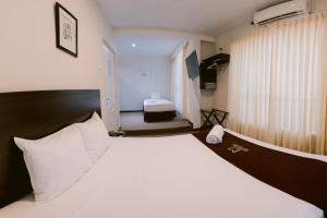 1 dormitorio con 1 cama grande con almohadas blancas en LM Hoteles, en Piura