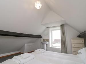 a bedroom with a white bed and a window at Stable Cottage in Whitby