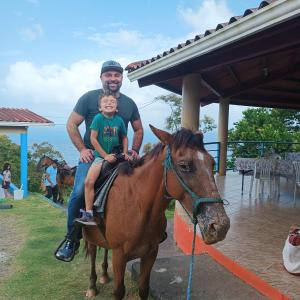 a man and a child sitting on a horse at Rancho Juancho in Portobelo