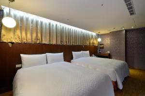 2 Betten in einem Hotelzimmer mit weißer Bettwäsche in der Unterkunft Hua Da Hotel- Nanxi in Taipeh