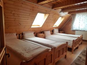 Cette chambre en bois comprend 2 lits et 2 fenêtres. dans l'établissement Antal Villa - 5mins to ski slope & 1min to skating, à Harghita-Băi