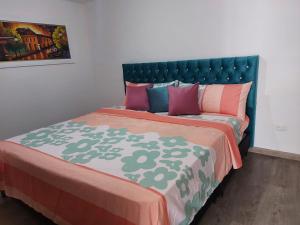 1 cama con cabecero verde y almohadas coloridas en Acogedor apartamento vacacional en zona centrica de Ibague, en Ibagué