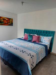 1 dormitorio con 1 cama con almohadas azules y rosas en Acogedor apartamento vacacional en zona centrica de Ibague, en Ibagué