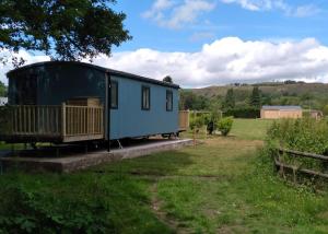 niebieska przyczepa siedząca na polu trawy w obiekcie Riverview Lodges And Glamping w mieście Welshpool