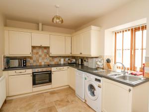 a kitchen with white cabinets and a sink and a dishwasher at Llaethdy in Cardigan
