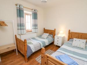 a bedroom with two beds and a window at Llaethdy in Cardigan