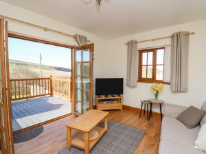 a living room with a couch and a tv and a balcony at Beudy in Cardigan