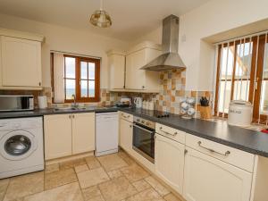 eine Küche mit weißen Schränken und einem Herd mit Backofen in der Unterkunft Beudy in Cardigan