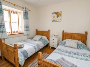 a bedroom with two beds and a window at Beudy in Cardigan