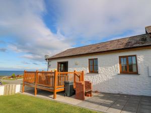 a white house with a wooden deck and the ocean at Beudy in Cardigan