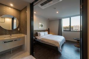 a bedroom with a bed and a sink and a mirror at Browndot hotel Guseo in Busan