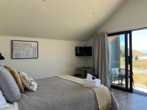 a bedroom with a bed and a sliding glass door at The Quarters Unit 1 - Lake Tekapo in Lake Tekapo