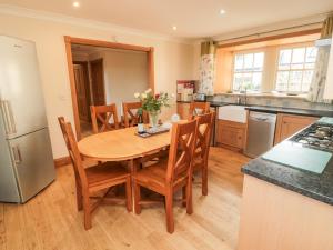 eine Küche mit einem Holztisch mit Stühlen und einem Kühlschrank in der Unterkunft Low Croft in Alnwick