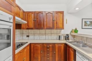 a kitchen with wooden cabinets and a sink at Fuller Holidays-Unit Pacific in Byron Bay +2 photos