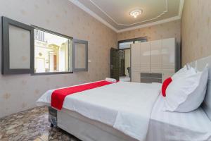 ein Schlafzimmer mit einem großen weißen Bett mit einer roten Decke in der Unterkunft RedDoorz Plus @ Villa Bontes Batu in Batu