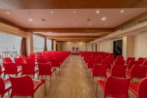 a conference room with red chairs and a stage at Hotel Tamizh Park in Pondicherry