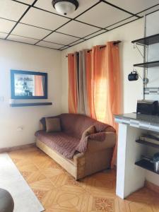 a couch sitting in a living room with orange curtains at Ofiuras Hostal in Colón