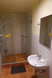 a bathroom with a glass shower and a sink at Sunset INN by Pro-Ema in Dili