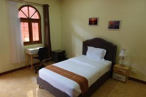 um quarto com uma cama, uma secretária e uma janela em Sunset INN by Pro-Ema em Dili