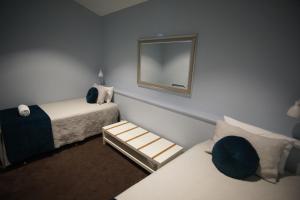 a small room with two beds and a mirror at Margaret River Mainstreet in Margaret River Town