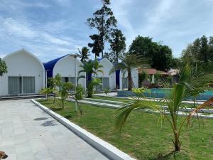 un complejo con piscina y palmeras en Kampheak Roath Bungalows, en Kampot
