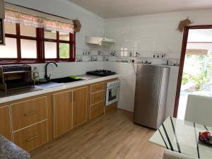 uma cozinha com armários de madeira e um frigorífico de aço inoxidável em Orchid Sunset Guest House em Baie Lazare Mahé