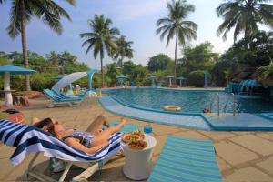 a woman laying on a beach chair next to a pool at Paradise Village Beach Resort in Calangute