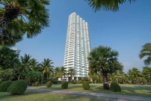 a tall building with palm trees in front of it at Ocean Portofino/Luxury2BR/153SQM in Na Jomtien