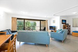 sala de estar con 2 sillas azules y sofá en Lahaina Apartments, en Mooloolaba