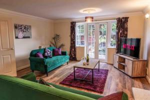 a living room with a green couch and a tv at Spacious 5 bedroom house in quiet cul-de-sac in Shrewsbury