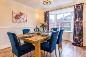 a dining room with a wooden table and blue chairs at Spacious house in quiet cul-de-sac near to Hospital in Shrewsbury