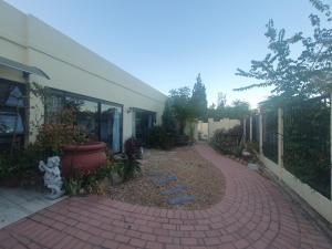 a brick walkway in front of a building with a garden at DOTJJ B & B in Paarl