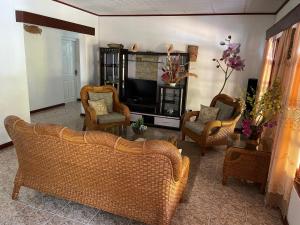 a living room with wicker chairs and a television at Orchid Sunset Guest House in Baie Lazare Mahé