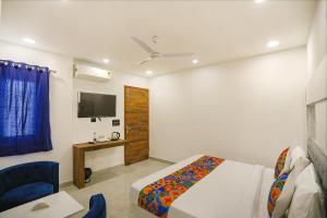 Schlafzimmer mit einem Bett, einem TV und einem Stuhl in der Unterkunft FabExpress F9 Noida Sector 27 in Noida