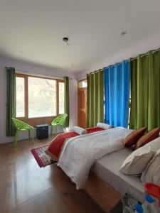 a bedroom with a large bed with green curtains at The Stone Palace Turtuk in Nubra